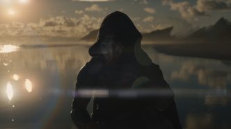 Dek, the young Predator outcast, under a blazing red sunset in Predator: Badlands.