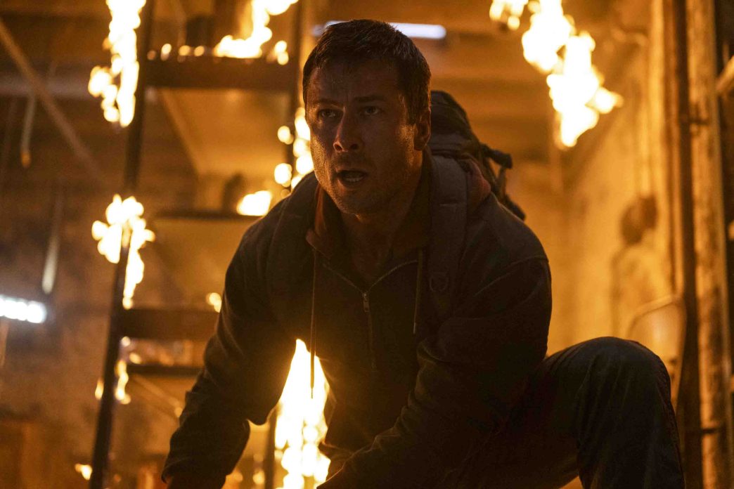 Glen Powell as Ben Richards sprinting through a holographic arena under red laser fire in The Running Man (2025), directed by Edgar Wright.