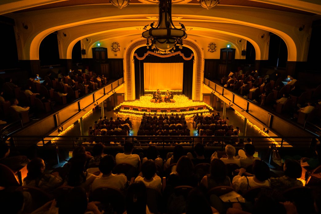 Candlelight concert performance with string musicians surrounded by candles in an intimate venue